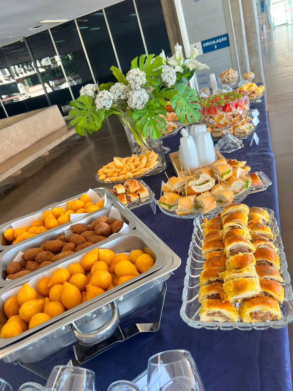 Rechauds com coxinhas e quibes ao lado de sanduiches e folhados