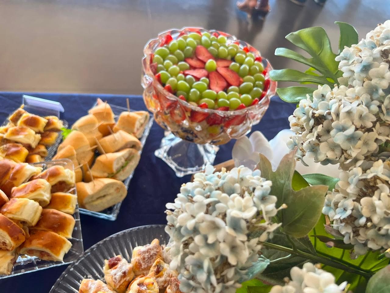 Taca de cristal com salada de frutas ao lado de arranjo floral