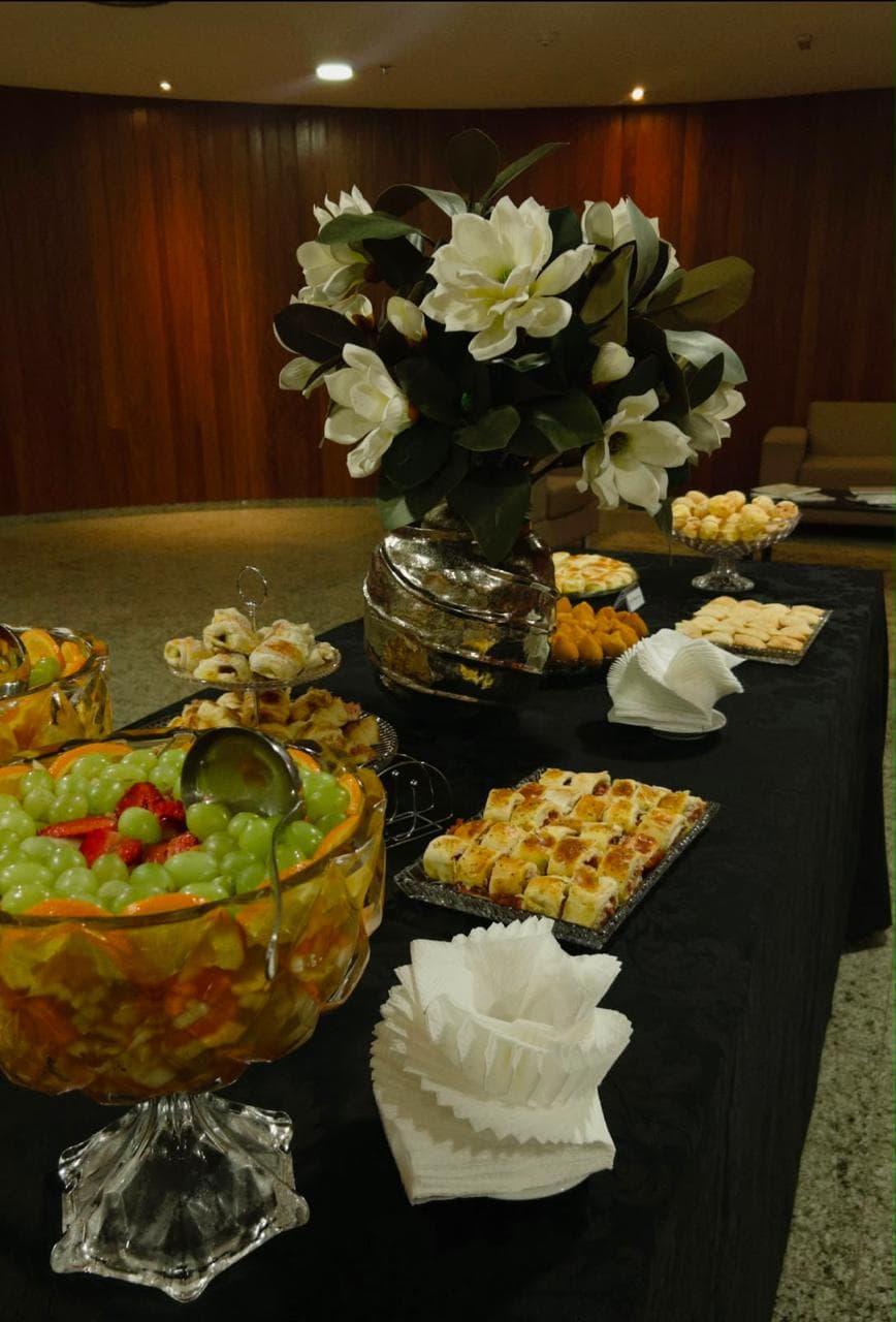 Mesa com toalha preta e arranjo de flores brancas em salao com painel de madeira