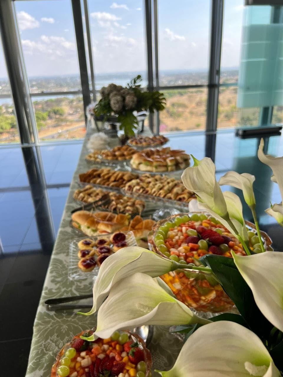 Mesa de buffet diante de janelas com vista panoramica da cidade